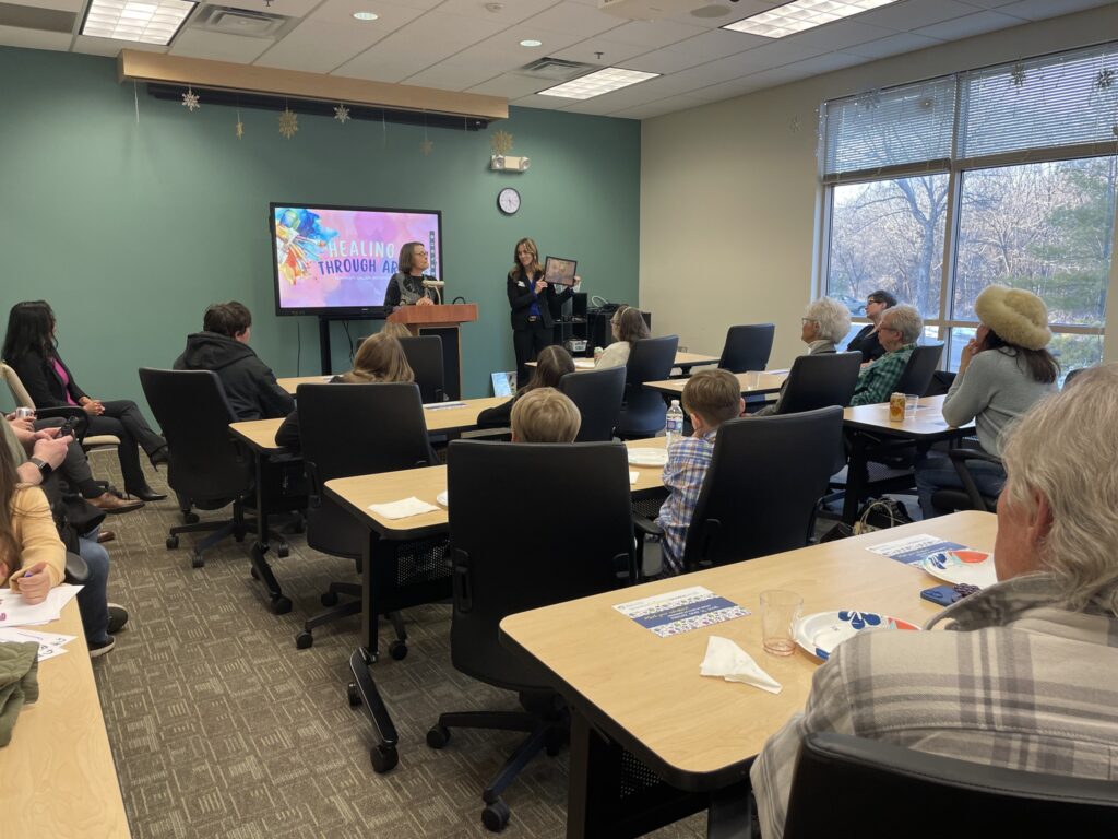 A client of Mind & Spirit Counseling Center shares the inspiration behind her art piece at the gallery event.